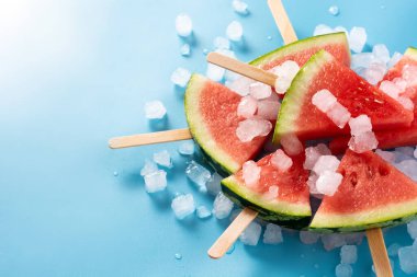 Karpuz, buzlu dondurmaları mavi arka planda dilimliyor. Boşluğu kopyala