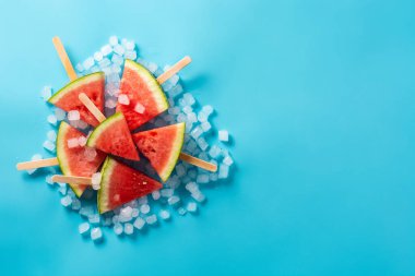 Karpuz, buzlu dondurmaları mavi arka planda dilimliyor. Üst Manzara. Boşluğu kopyala