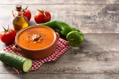 Güveç kabında gazpacho çorbası ve ahşap masada malzeme. Boşluğu kopyala