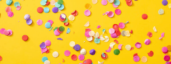 Colorful confetti on yellow background.