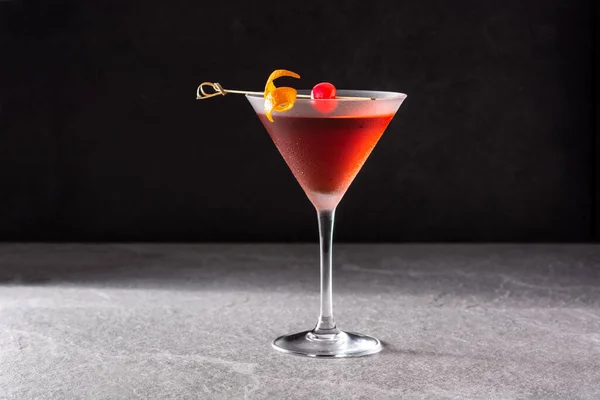 Traditional Manhattan cocktail with cherry on black background