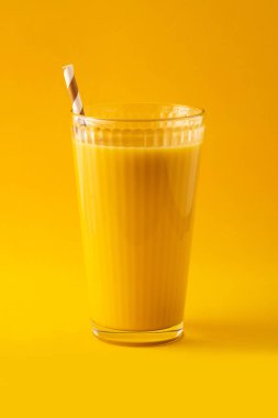 Sarı arka planda cam kaplı vanilyalı milkshake.
