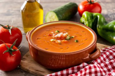 Güveç tenceresinde gazpacho çorbası ve ahşap masada malzeme.
