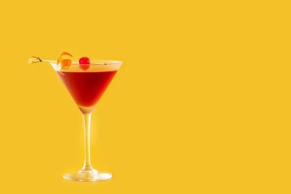 Traditional Manhattan cocktail with cherry on yellow background. Copy space