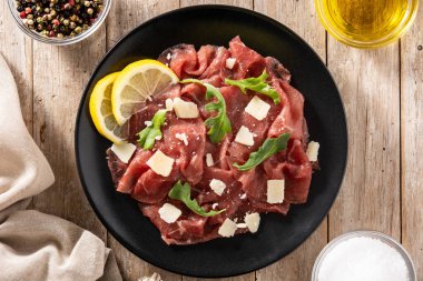 Köy ahşap masada siyah tabakta mermer bir carpaccio.