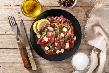 Köy ahşap masada siyah tabakta mermer bir carpaccio.