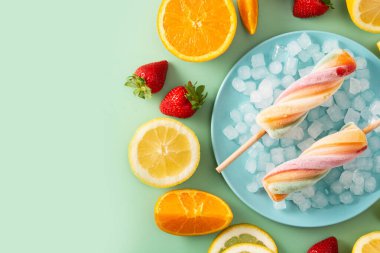 Yeşil arka planda meyveli sarmal renkli buzlu dondurma. Üst Manzara. Boşluğu kopyala