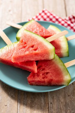 Karpuz, buzlu dondurmaları mavi tabakta kırsal ahşap masada keser.