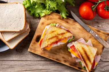 Domatesli sandviç, marul, jambon ve peynirli ahşap masa. Üst görünüm