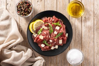Siyah tabakta mermer sığır carpaccio ve kırsal ahşap masa. Üst görünüm