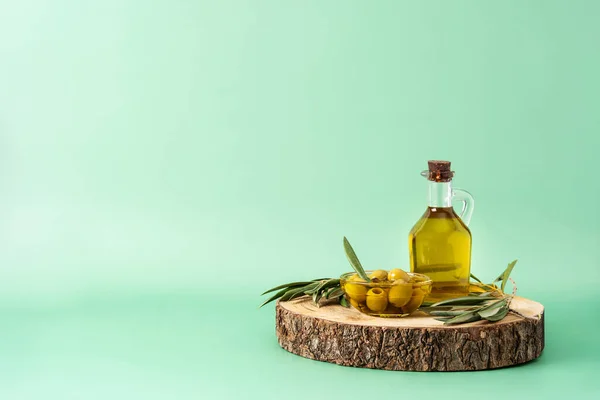 Virgin olive oil bottle and green olives on green background. Copy space