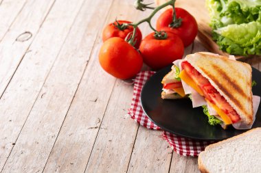 Domatesli sandviç, marul, jambon ve peynirli ahşap masa.