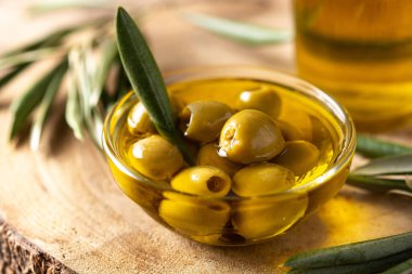 Ahşap masadaki kristal kasede yeşil zeytinli saf zeytin.