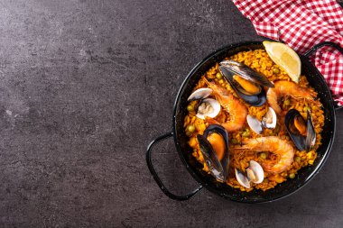 Siyah arka planda geleneksel İspanyol deniz ürünleri paella 'sı. Üst Manzara. Boşluğu kopyala