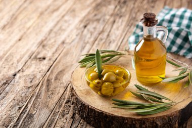 Virgin olive with green olives in crystal bowl on wooden table. Copy space