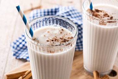 Fresh horchata with cinnamon in glass on rustic wooden table clipart