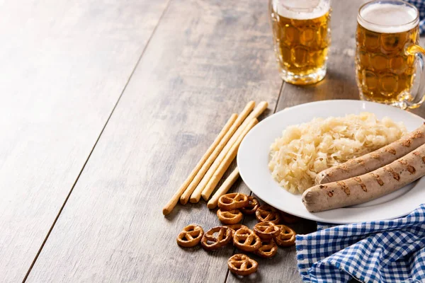 木製のテーブルの上にBratwurstソーセージ ザワークラウト プレッツェル ビール 典型的なドイツ料理 — ストック写真