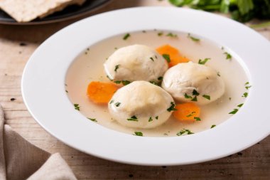 Geleneksel Yahudi matza topu çorbası ve ahşap masada matza ekmeği.