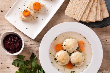 Geleneksel Yahudi matza topu çorbası, gefilte balığı ve ahşap masada matza ekmeği.