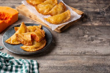 Ahşap masada balkabağı empanadillası. Boşluğu kopyala