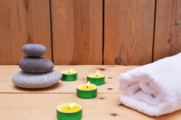 Velas, piedras zen y toalla sobre madera — Foto de Stock