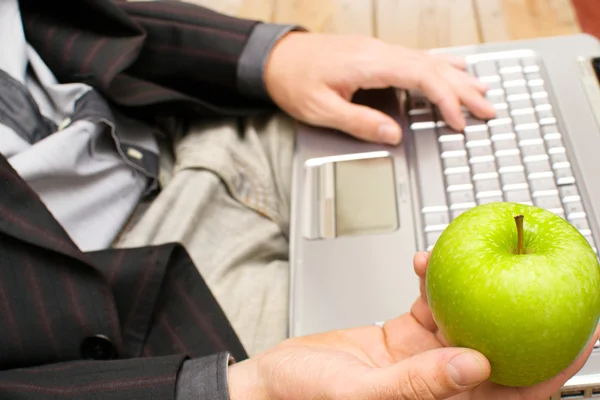 Affärsman med en dator och ett äpple i handen — Stockfoto