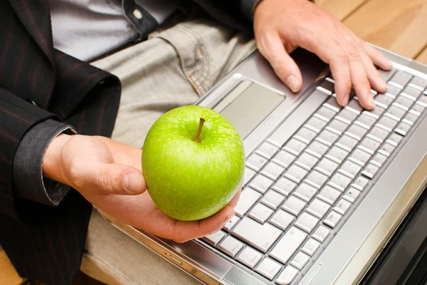 Affärsman med en dator och ett äpple i handen — Stockfoto