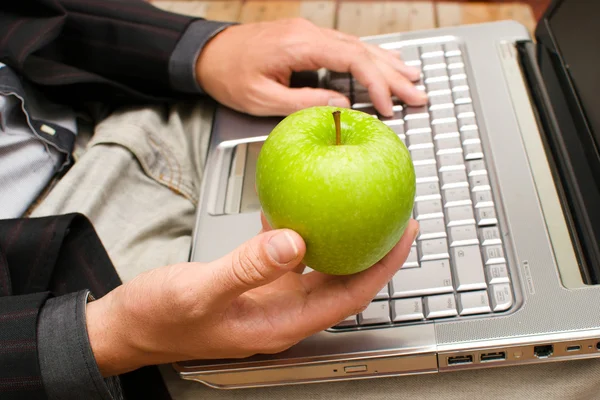 Affärsman med en dator och ett äpple i handen — Stockfoto