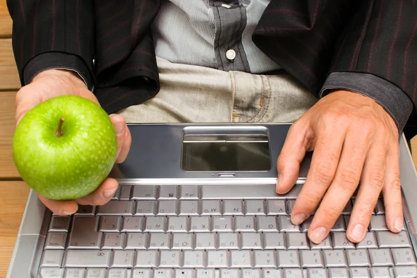 Affärsman med en dator och ett äpple i handen — Stockfoto