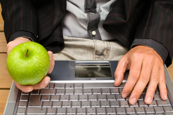 Affärsman med en dator och ett äpple i handen — Stockfoto