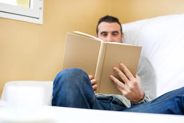Young man reading on the sofa for your home — Stock Photo, Image