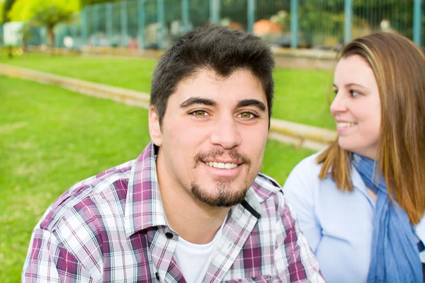 Young man and young woman smiling in park — Stock Photo, Image