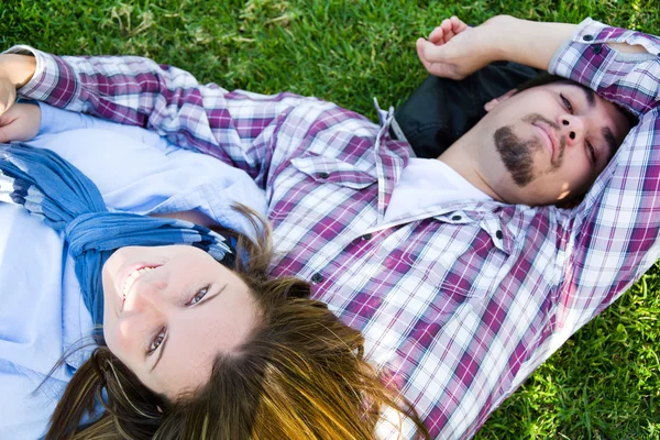 Casal deitado na grama em um parque — Fotografia de Stock