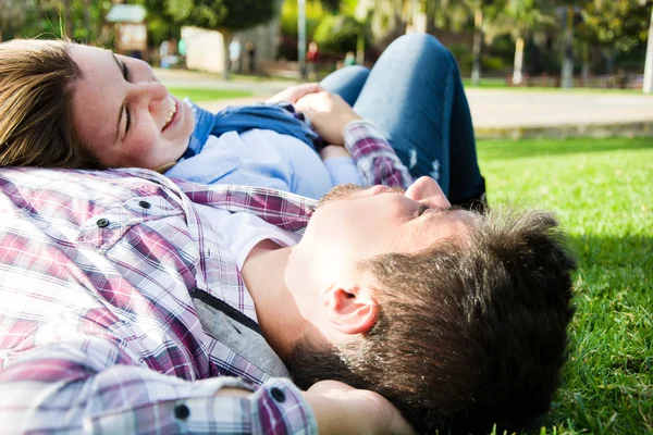 Couple lying on the grass in a park — Stock Photo, Image