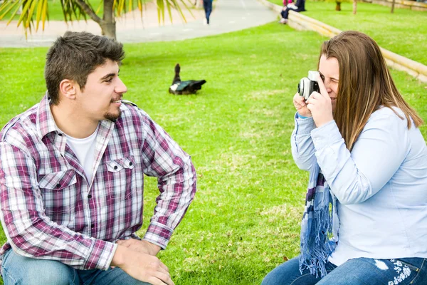 Young woman doing a photo to her boyfriend in the park — Stock Photo, Image