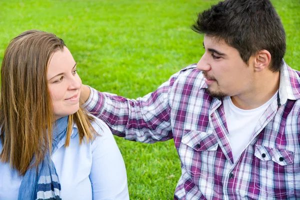Young man and young woman smiling in park — Stock Photo, Image