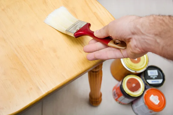 Homem envernizando uma cadeira com pincel — Fotografia de Stock