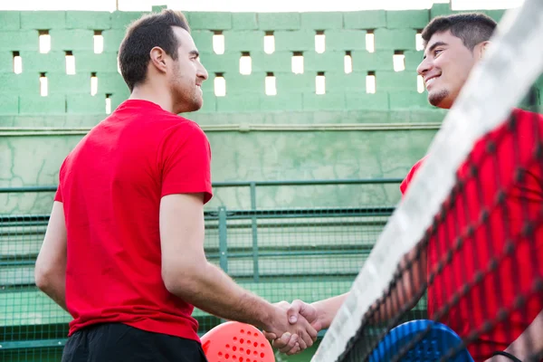 Friends shaking hands in paddle tennis field — Stock Photo, Image