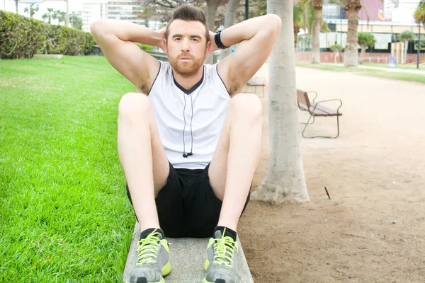 Man doing sit-ups in the park — Stock Photo, Image