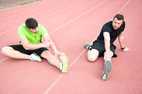Men stretching in running track — Stock Photo, Image