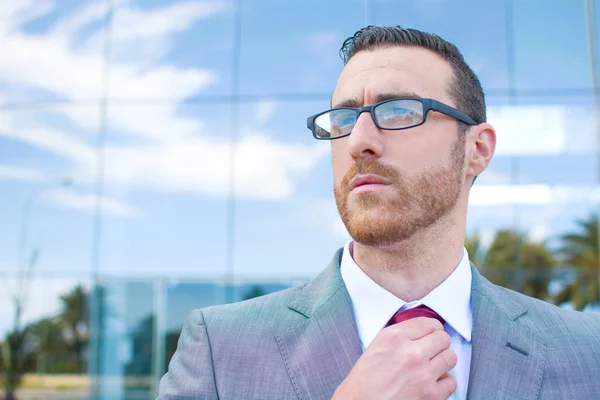 Zakenman zetten zijn das met kantoren in de achtergrond — Stockfoto