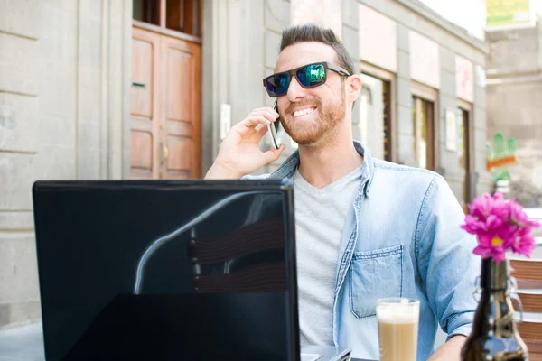 Young man with a laptop and a coffee on a terrace — Stock Photo, Image