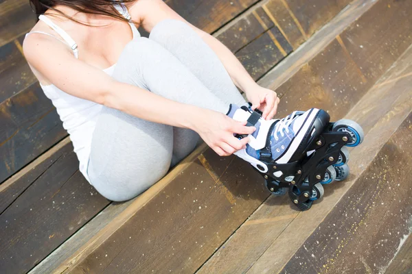 Mladá žena s roller-skates sedí na schodiště — Stock fotografie