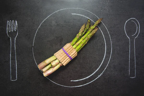 Asparagus on slate table. Plate, fork and spoon drawn with chalk — Stock Photo, Image