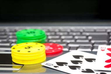 Dizüstü bilgisayar, poker kartları ve poker fişleri