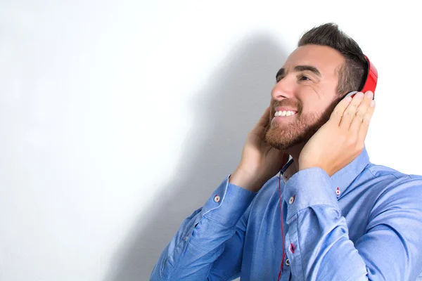 Hombre escuchando música con auriculares. Pared blanca con sombra —  Fotos de Stock