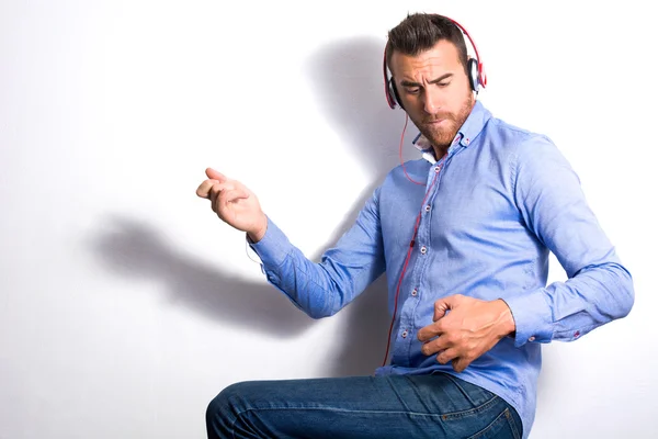 Man listening music with headphones and playing air guitar — Stock Photo, Image