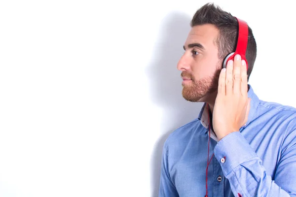 Hombre escuchando música con auriculares. Pared blanca con sombra —  Fotos de Stock