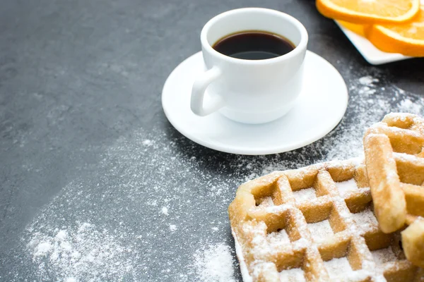 Waffles, café e laranjas na mesa de ardósia na cozinha — Fotografia de Stock