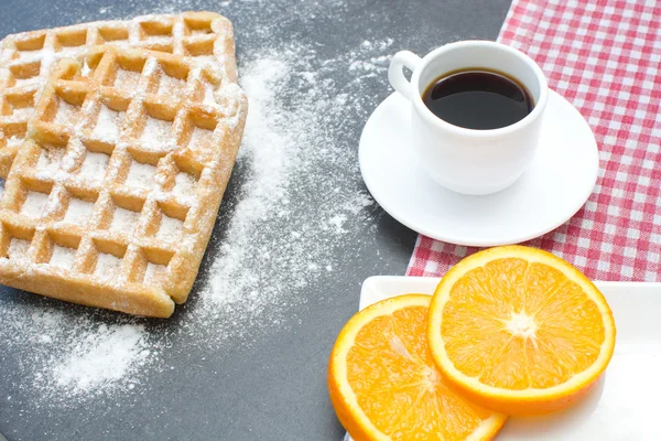 Waffeln, Kaffee und Orangen auf dem Schiefertisch in der Küche — Stockfoto